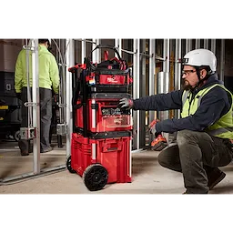 The PACKOUT Tool Box Magnetic Bin Attachment is shown being used on a construction site, attached to a red rolling tool box system.