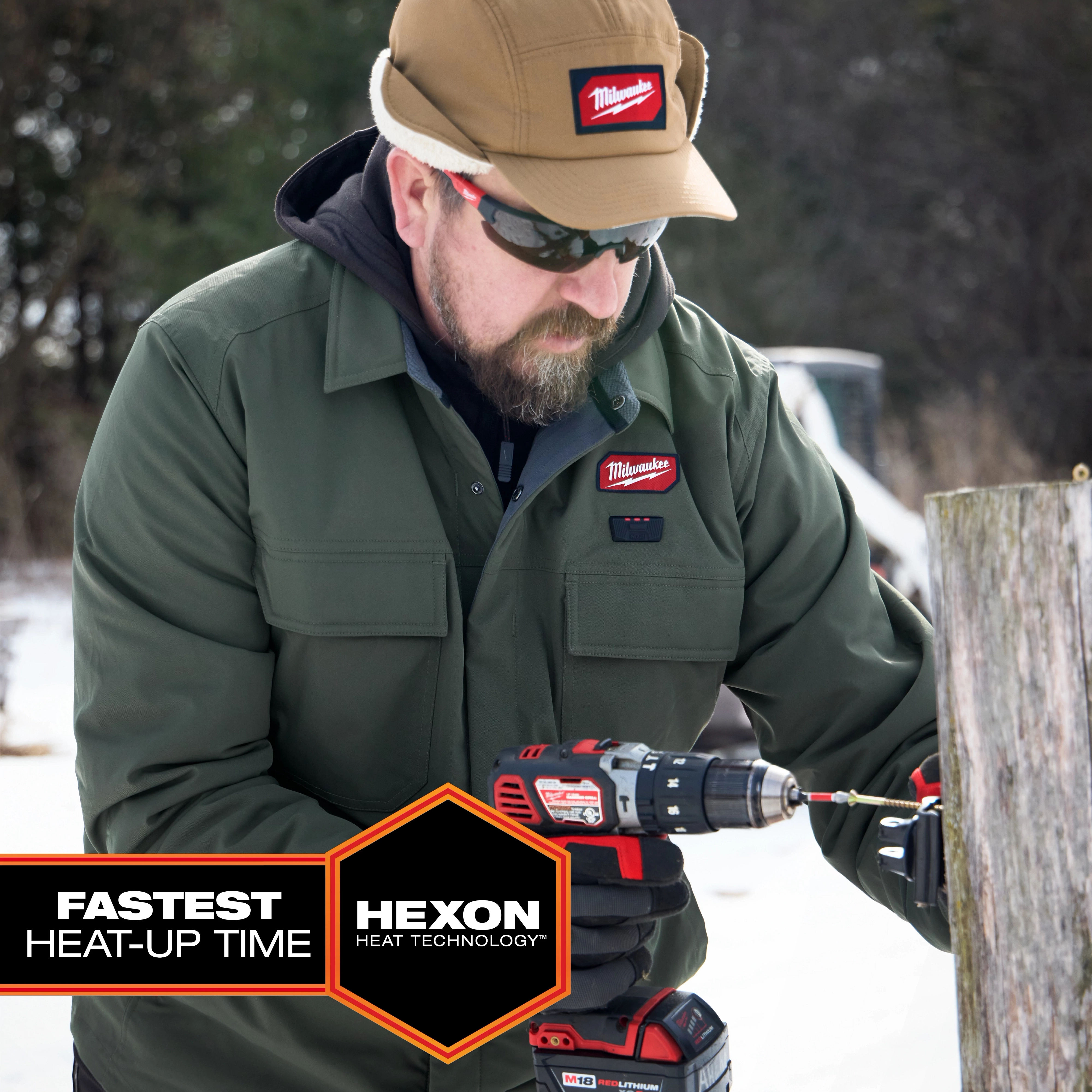 Person using a power drill outdoors while wearing an M12 Shirt Jacket - Green L in a snowy setting.