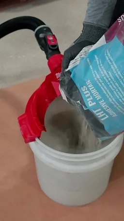 Milwaukee AIR-TIP Bucket Topper Dust Collector in action with adhesive mortar.