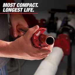 A person is using the Milwaukee pipe cutter to cut a metal pipe. The text on the image reads, "Most Compact. Longest Life." The Milwaukee logo is visible on the red pipe cutter.