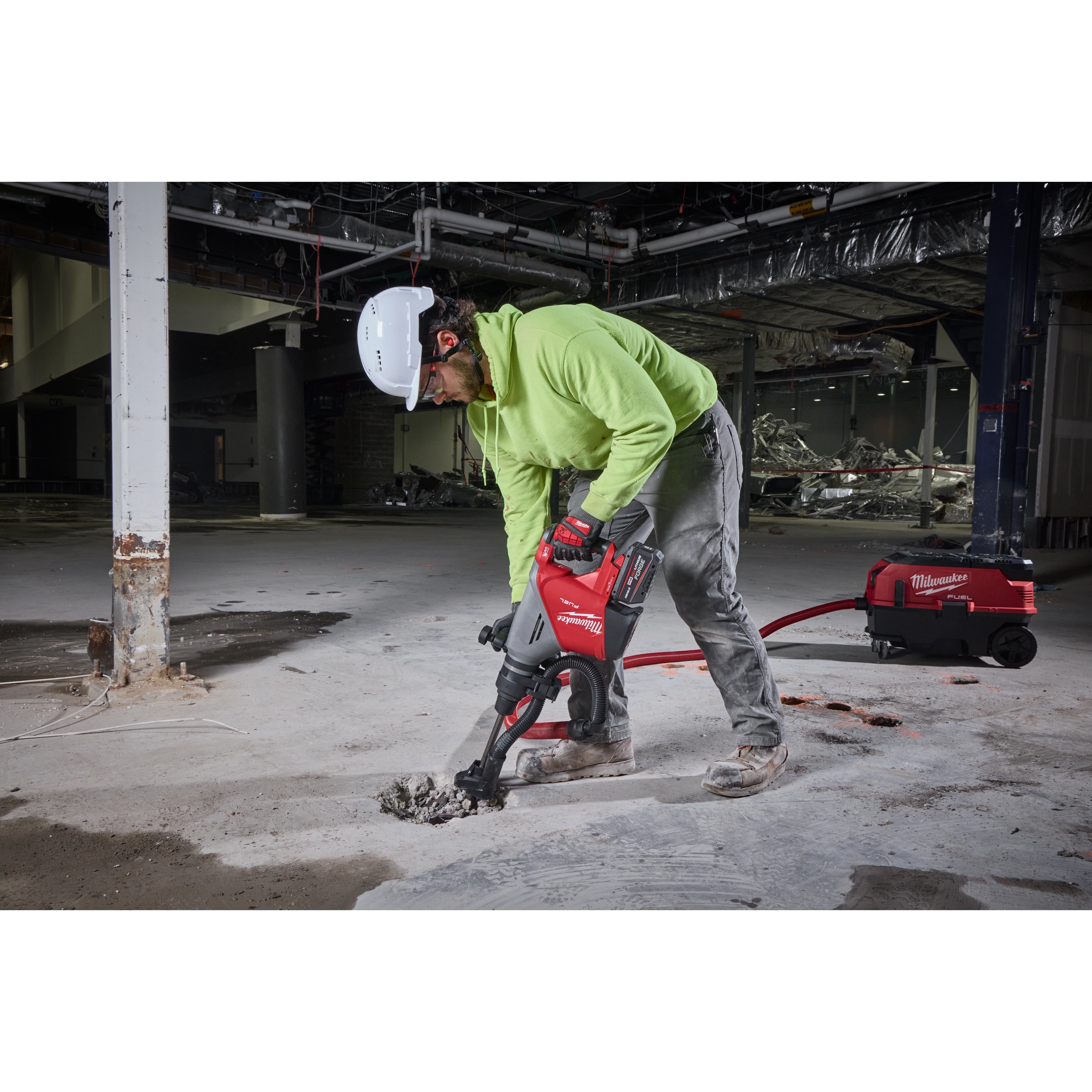 Person operating the M18 FUEL 18lb SDS MAX Demolition Hammer Kit to break concrete inside a partially demolished building.