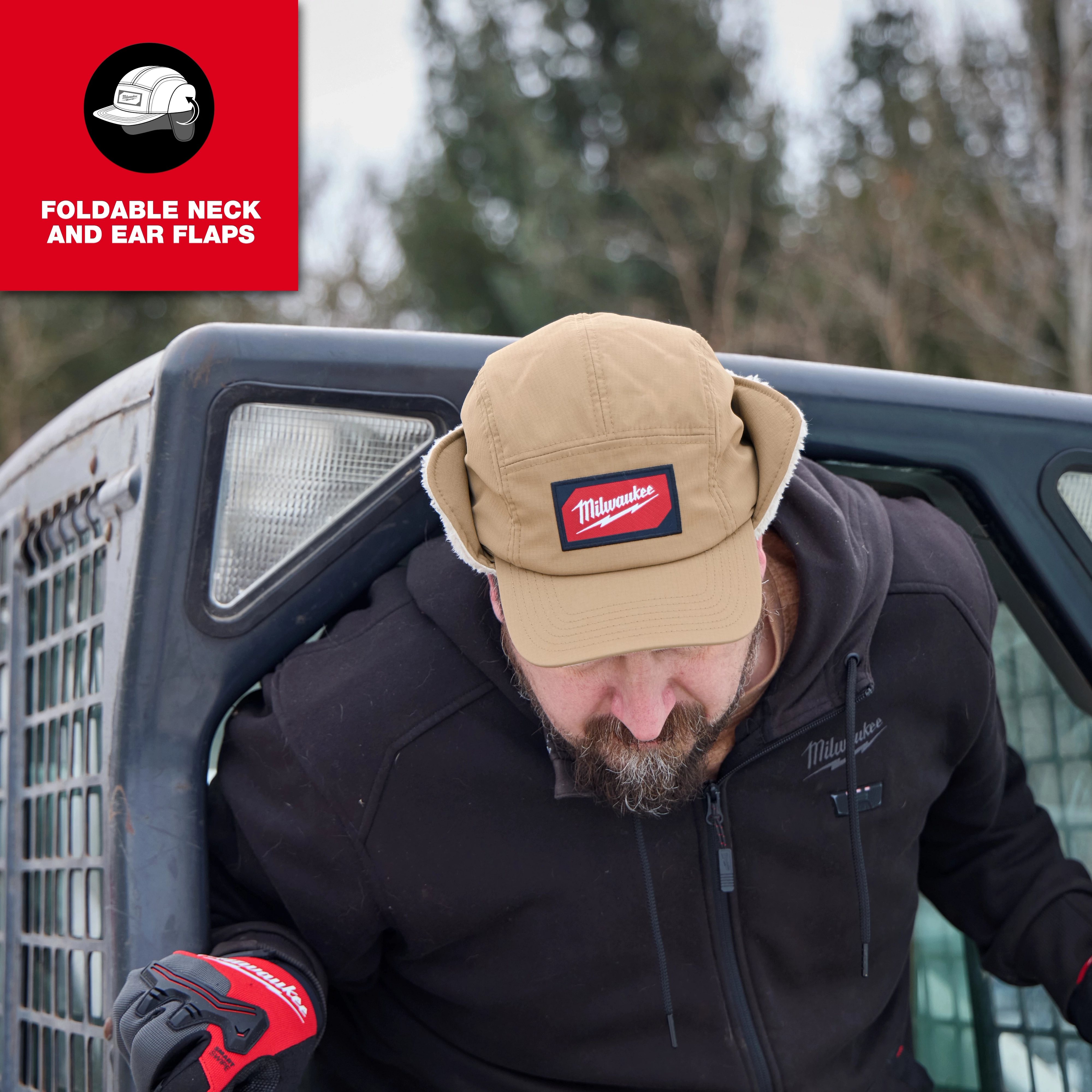 Person wearing a Milwaukee Sherpa-Lined Hat with ear flaps, leaning out of a vehicle in an outdoor setting.