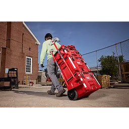 A person is pulling a PACKOUT Tool Box with a Long Tool Holder Attachment