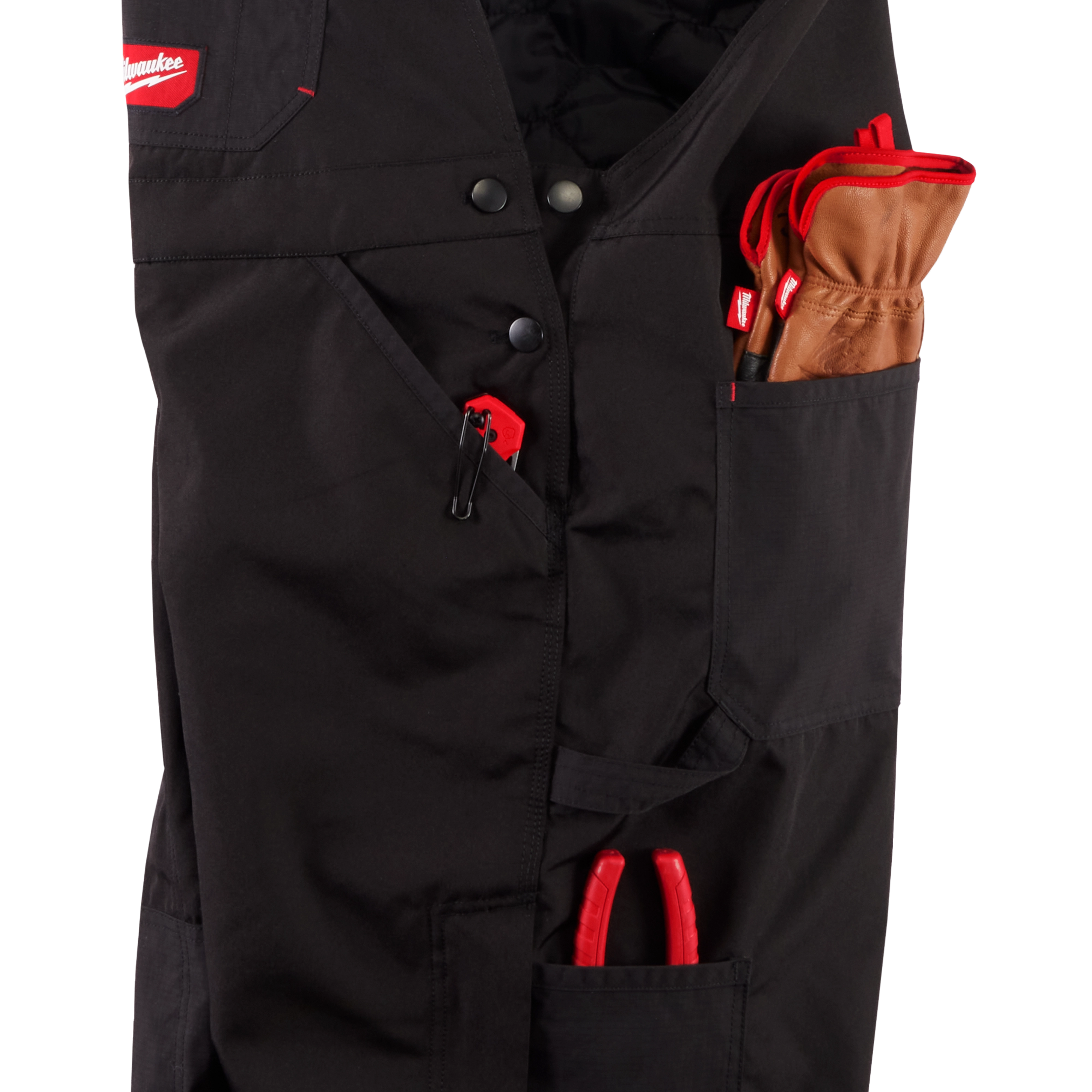 Close-up of the black FREEFLEX Insulated Bib Overalls, showcasing multiple pockets holding gloves, pliers, and a red zipper pull.