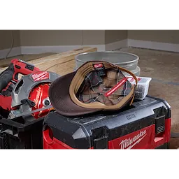 Waxed Canvas Adjustable Hat displayed on a red and black tool case in a workshop setting with power tools in the background.