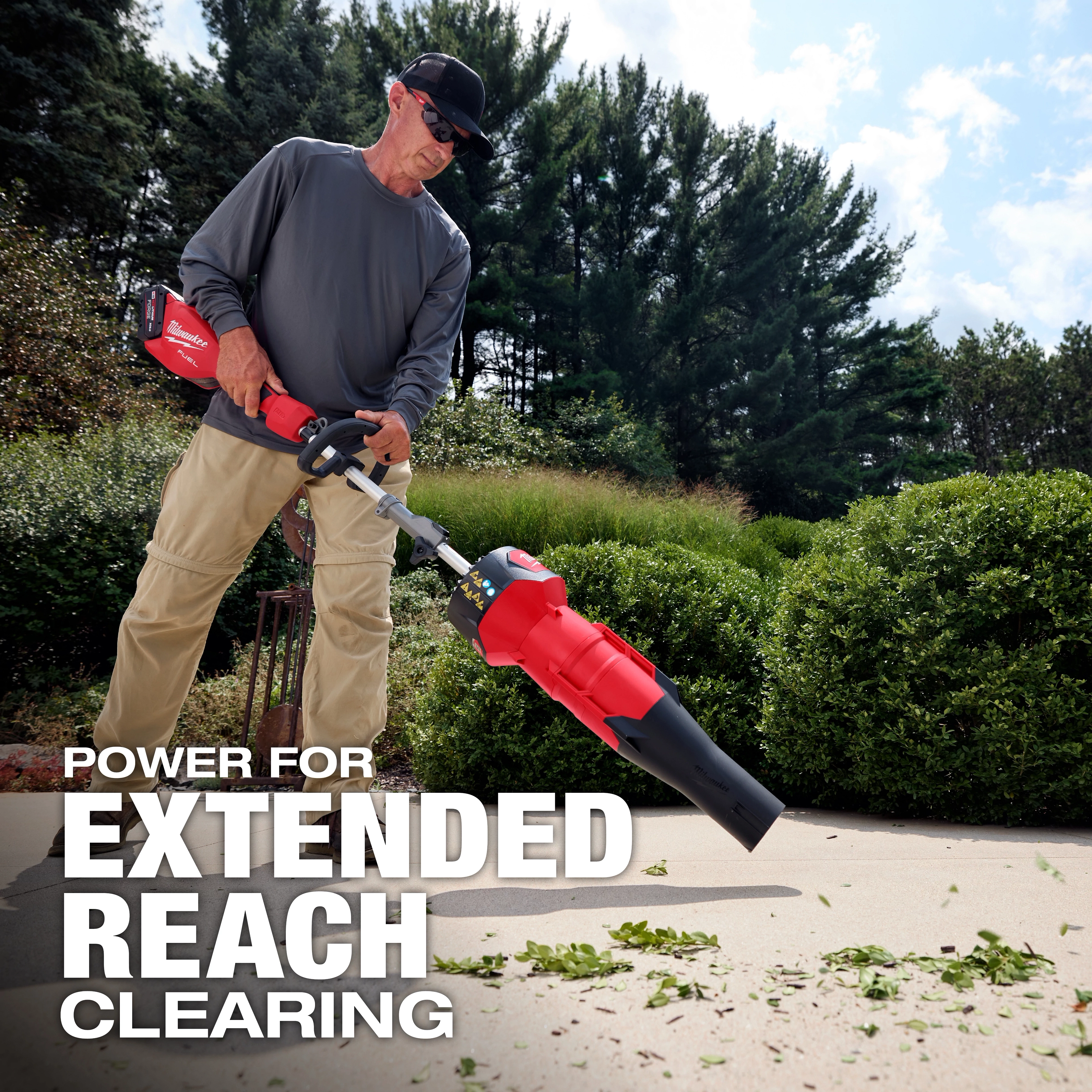 Person using an M18 FUEL QUIK-LOK Blower Attachment to clear leaves from a walkway.