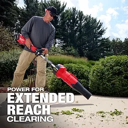 Person using an M18 FUEL QUIK-LOK Blower Attachment to clear leaves from a walkway.
