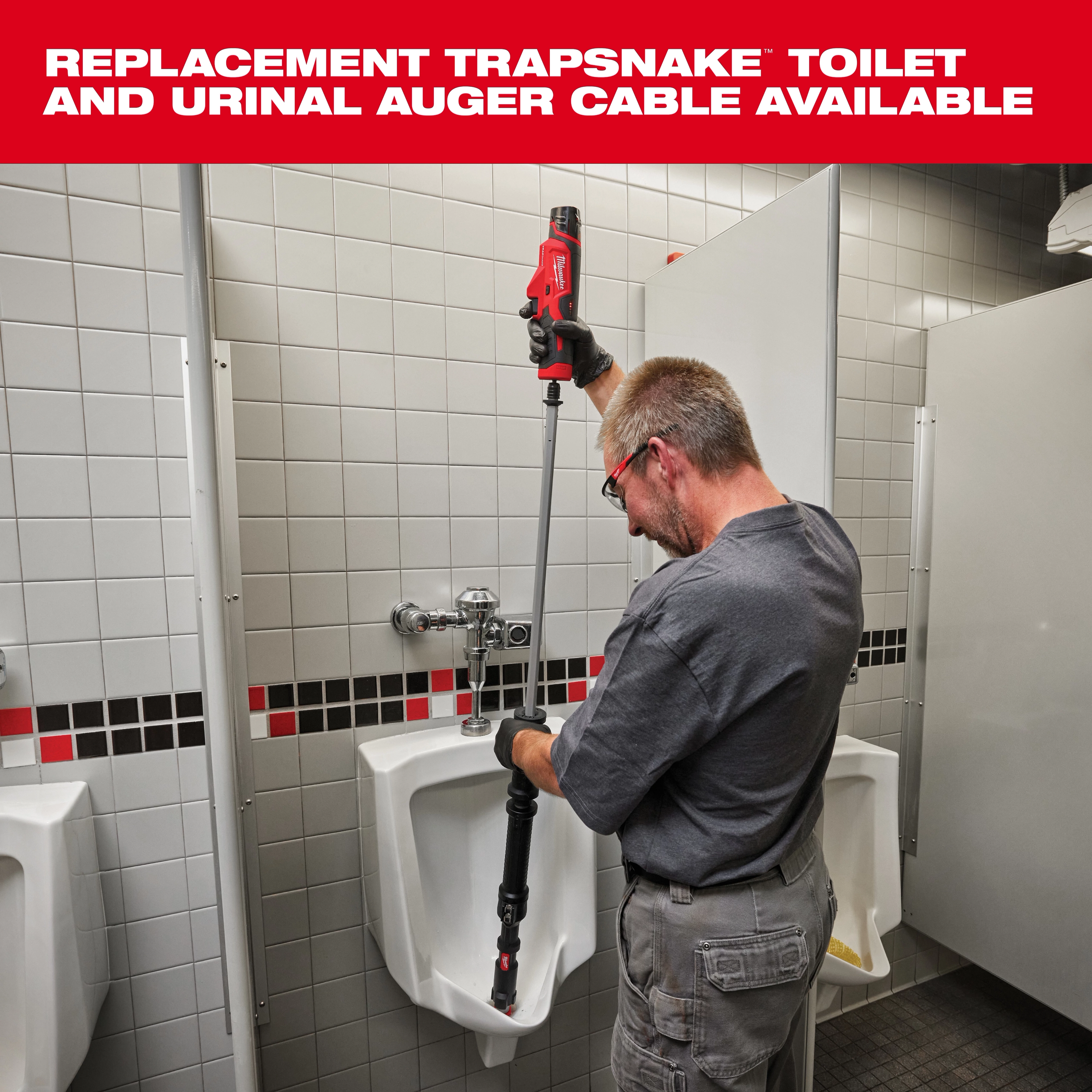 A plumber uses the TRAPSNAKE toilet and urinal auger cable in a public restroom with tiled walls and urinals. The tool has a red handle and a long flexible shaft, designed for unclogging and cleaning urinals and toilets efficiently. Replacement cables are available.