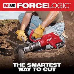 The M18 FORCE LOGIC Underground Cable Cutter is being used by a worker wearing gloves and jeans to cut a thick cable underground. The device is held with both hands, and the cutting process is taking place in a dirt trench.