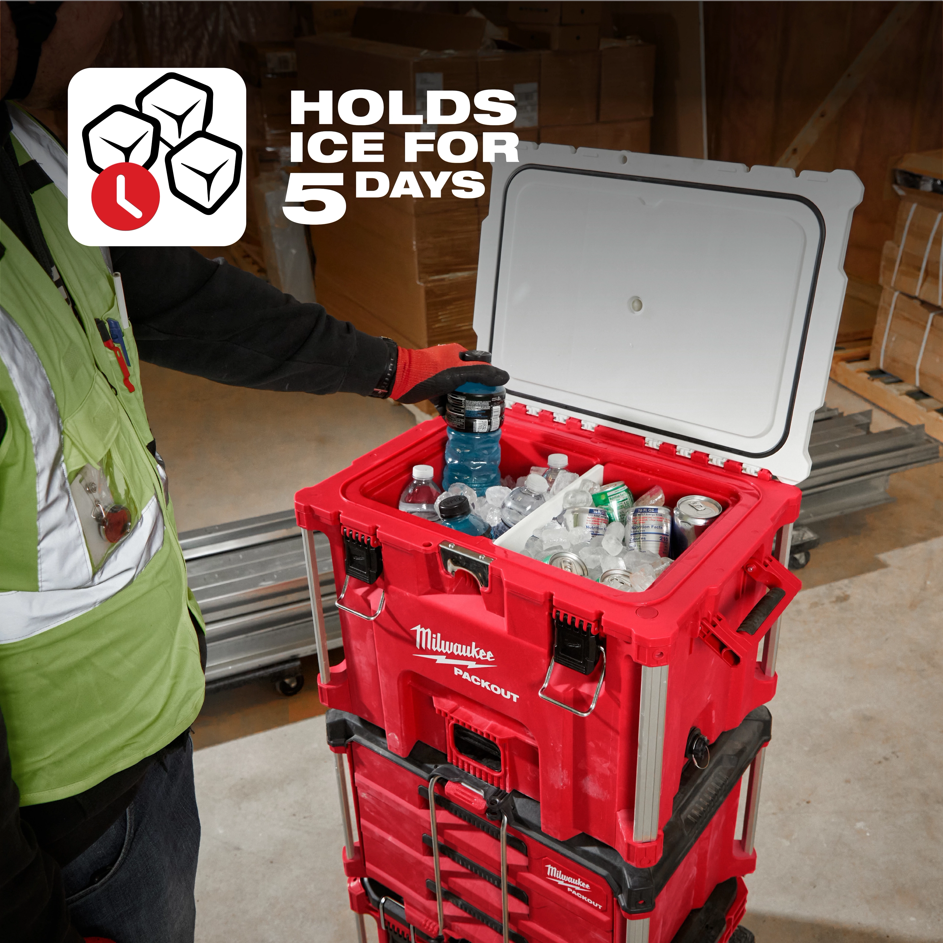 PACKOUT 40QT XL Cooler filled with drinks. Text says "holds ice for 5 days." Person in a green safety vest placing a drink into it.
