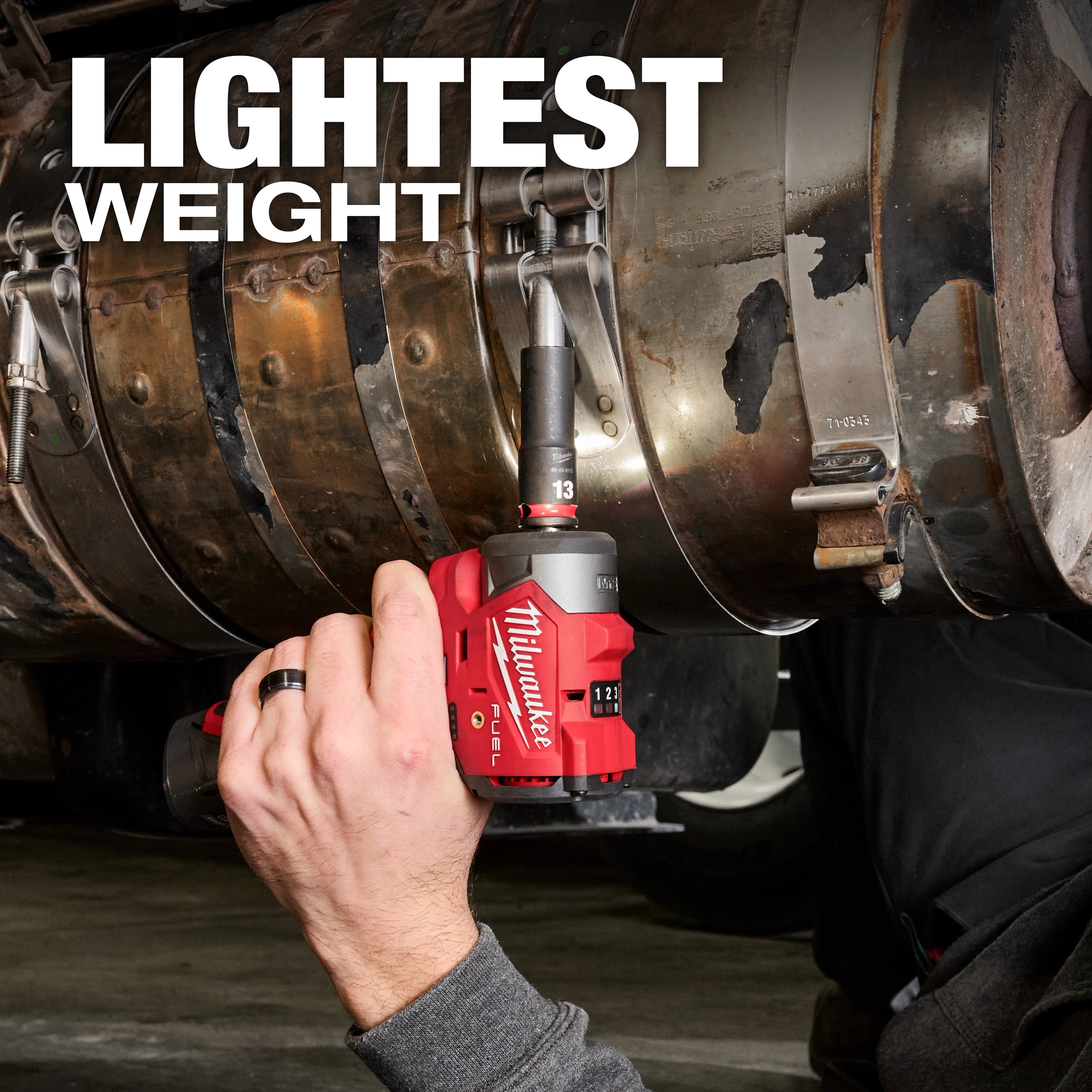 A person uses a Milwaukee M12 FUEL™ 3/8" Subcompact Impact Wrench with Friction Ring on a large metal pipe with text "LIGHTEST WEIGHT" above.