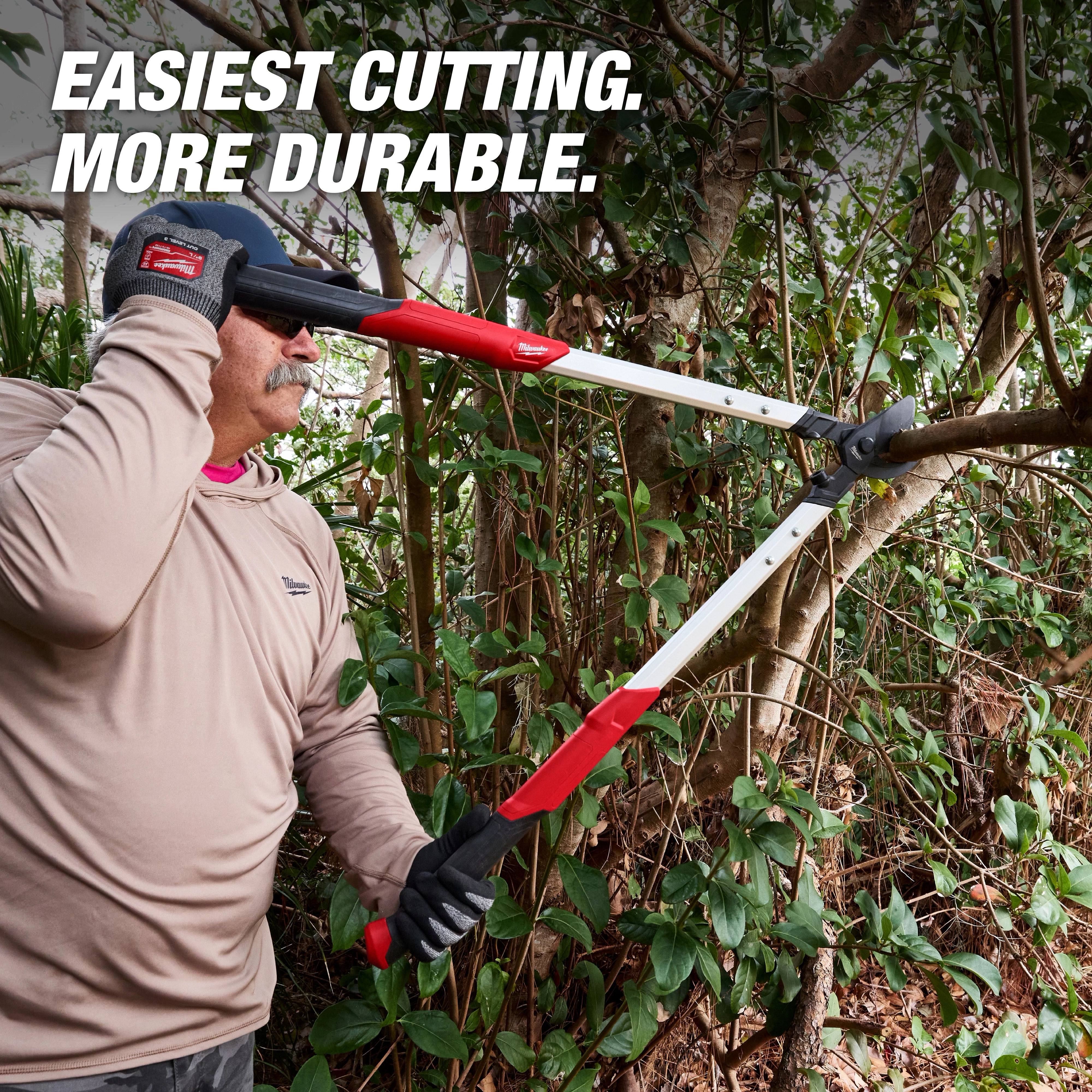 A person uses a 2” Lopper to cut a tree branch. The tool has long handles with red grips and is designed for durability and ease of cutting. The background includes bushes and trees, while the text reads “Easiest cutting. More durable.”