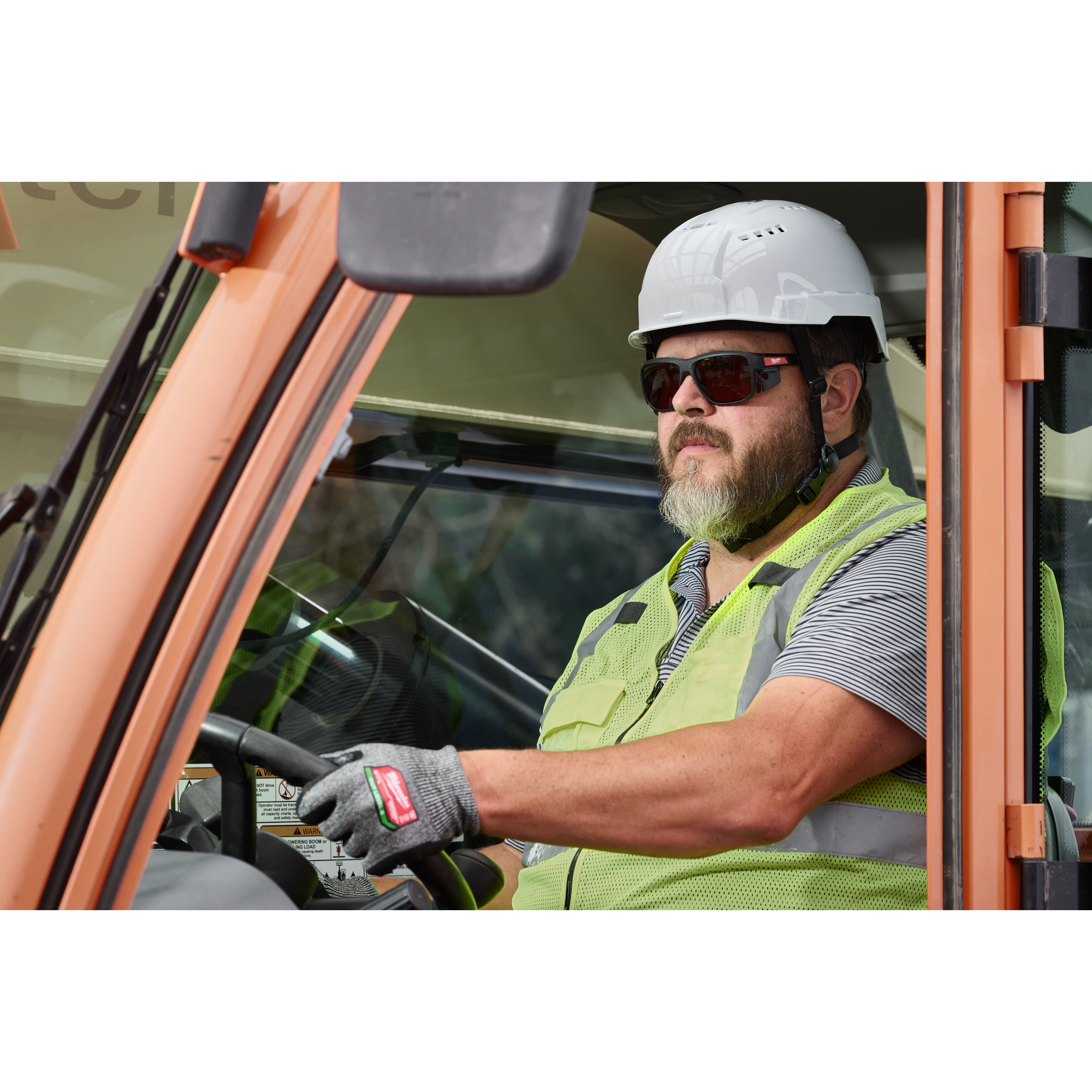 A construction worker wearing a white helmet, green safety vest, and gloves is operating machinery. The worker is also wearing Full Frame Safety Glasses with Removable Side Shields – Silver Mirrored Anti-Scratch Lenses.