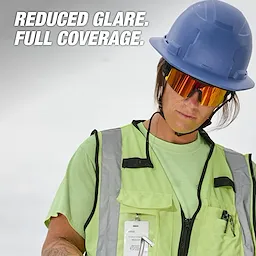 A person in a green safety vest and blue hard hat wears Polarized Wrap Around Safety Glasses - Red Mirrored Dual Coat Lens. Text reads "Reduced Glare. Full Coverage."