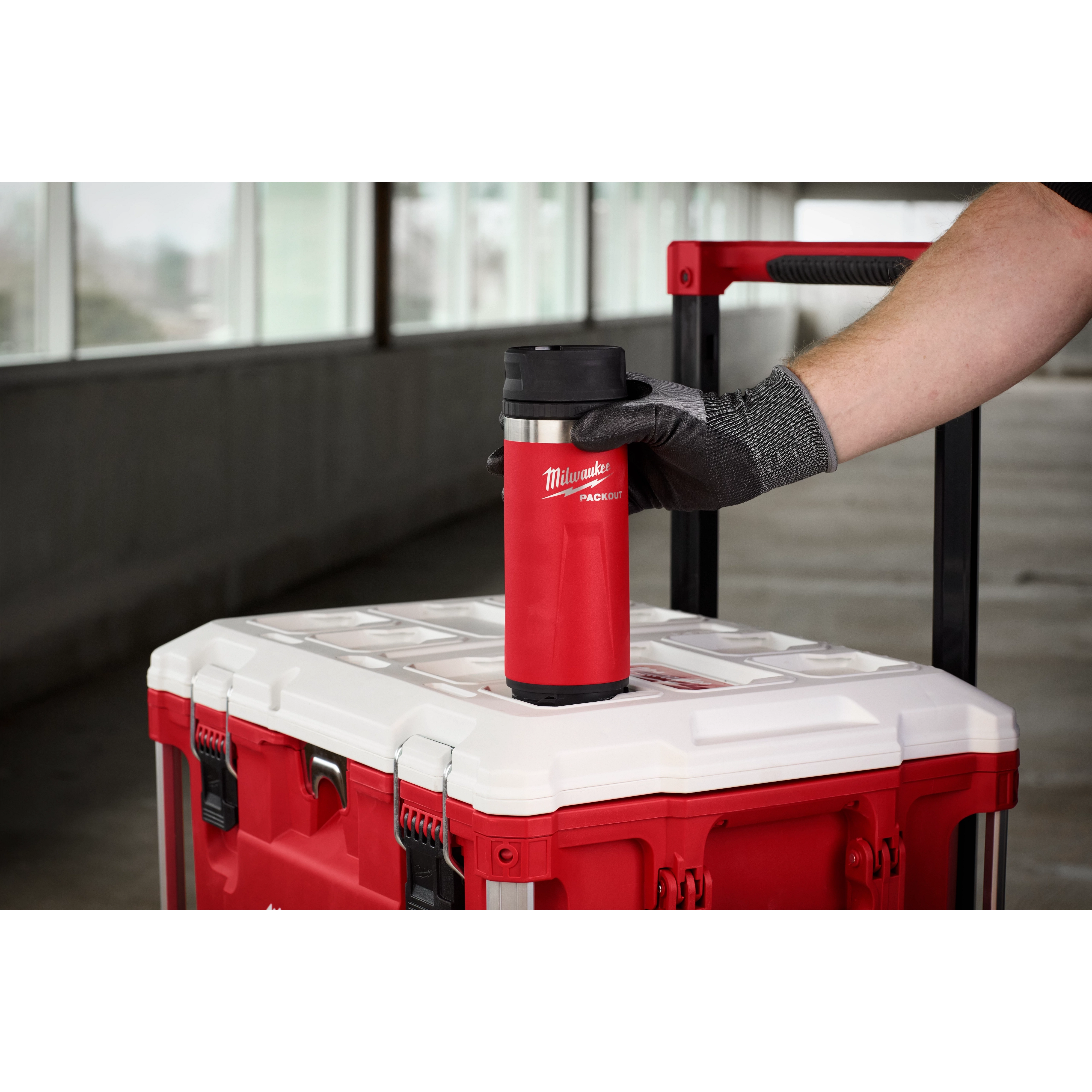 Person places a red PACKOUT 18oz Insulated Bottle with Sip Lid on top of a matching red and white carrying case with a handle.