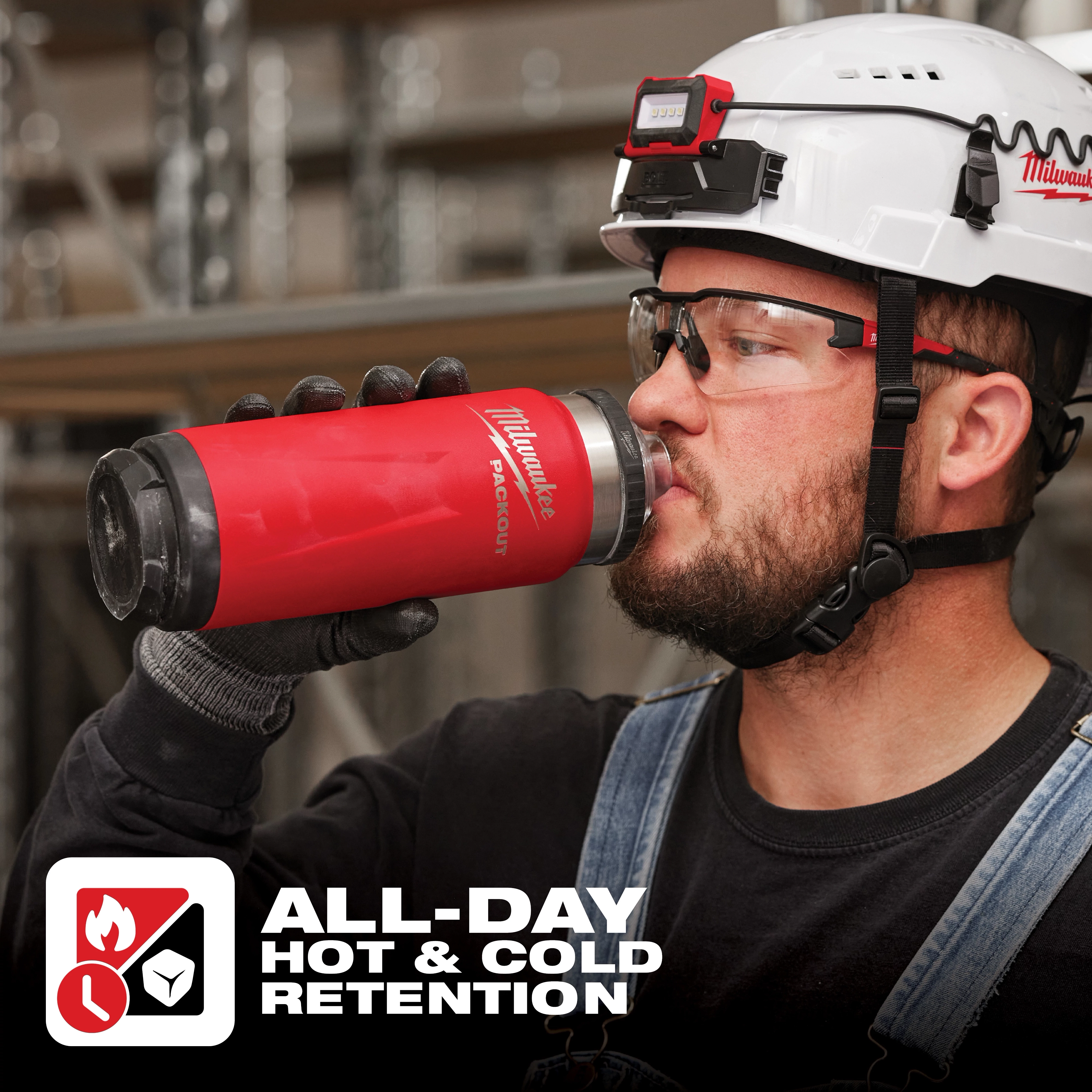 Worker holding a red App%20Shot%20Overlay stainless steel insulated bottle with "All-Day Hot & Cold Retention" text at the bottom.