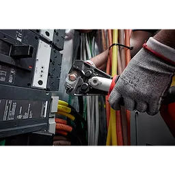 A gloved hand operates a 750 MCM Cu/Al Cutting Jaw, cutting through electrical cables in an industrial setting.