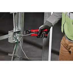 A person wearing gloves is using a Self-Adjusting Wire Stripper & Cutter to strip wires attached to a metal frame.