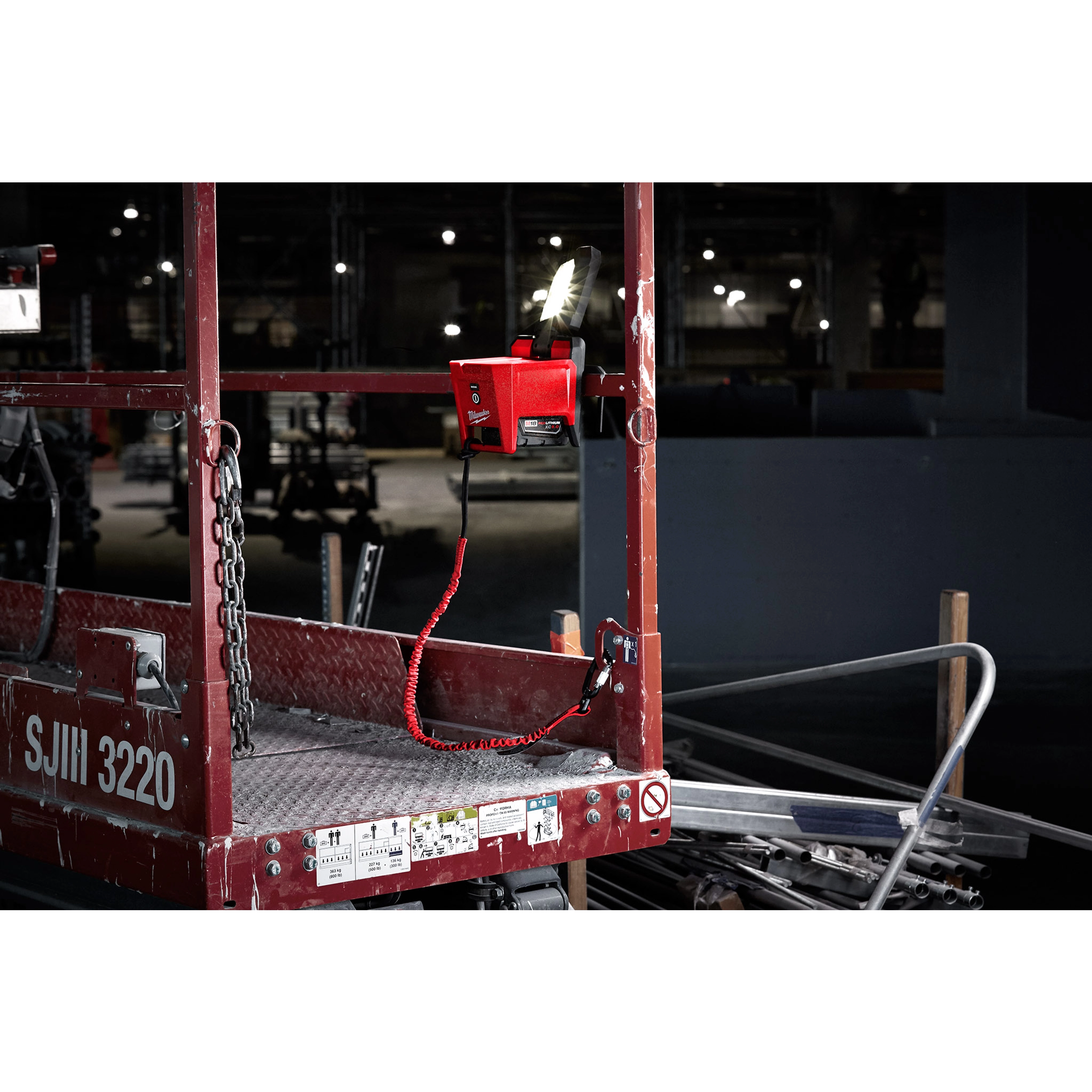Locking Tool Lanyard attached to a red scaffolding platform in a dimly lit industrial setting.