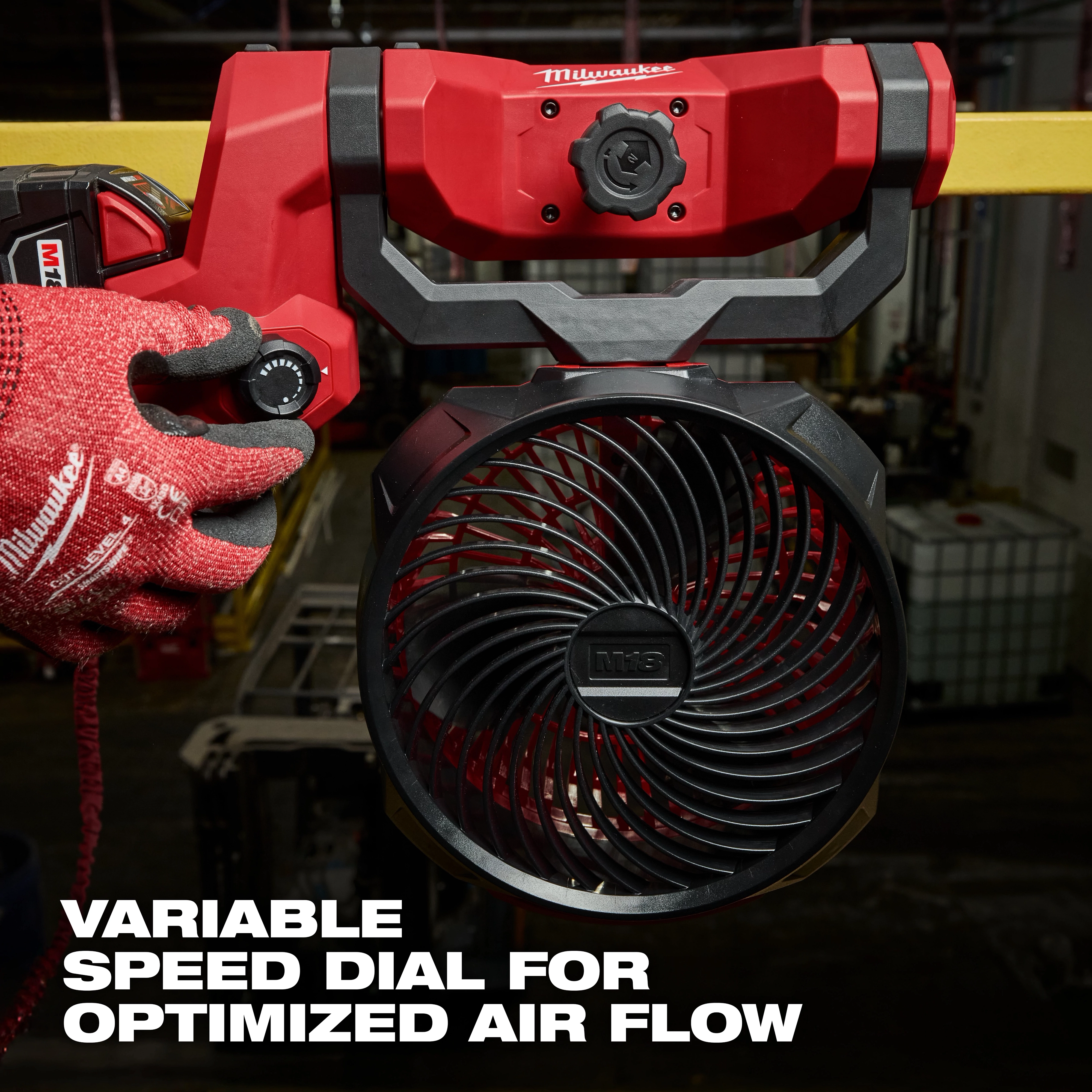 M18 Brushless Scissor Lift Fan with a variable speed dial for optimized airflow, handled by a person wearing red gloves.