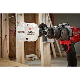 A 2" Hole Dozer with Carbide Teeth attached to a red and black power drill, set in a construction environment.