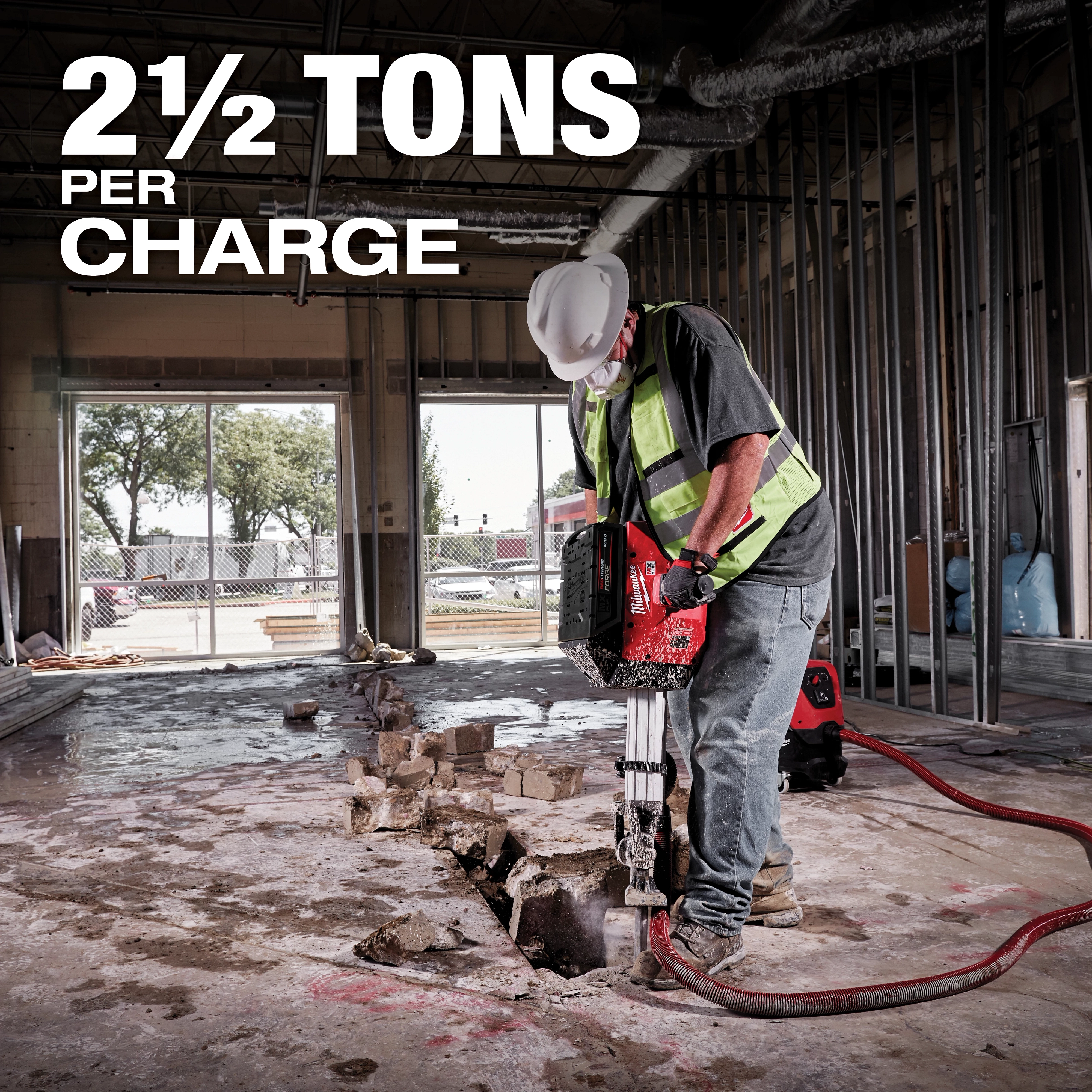 Worker using MX FUEL Breaker Kit on concrete indoors, with text overlay "2½ TONS PER CHARGE" highlighting the tool's power.