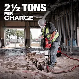 Worker using MX FUEL Breaker Kit on concrete indoors, with text overlay "2½ TONS PER CHARGE" highlighting the tool's power.