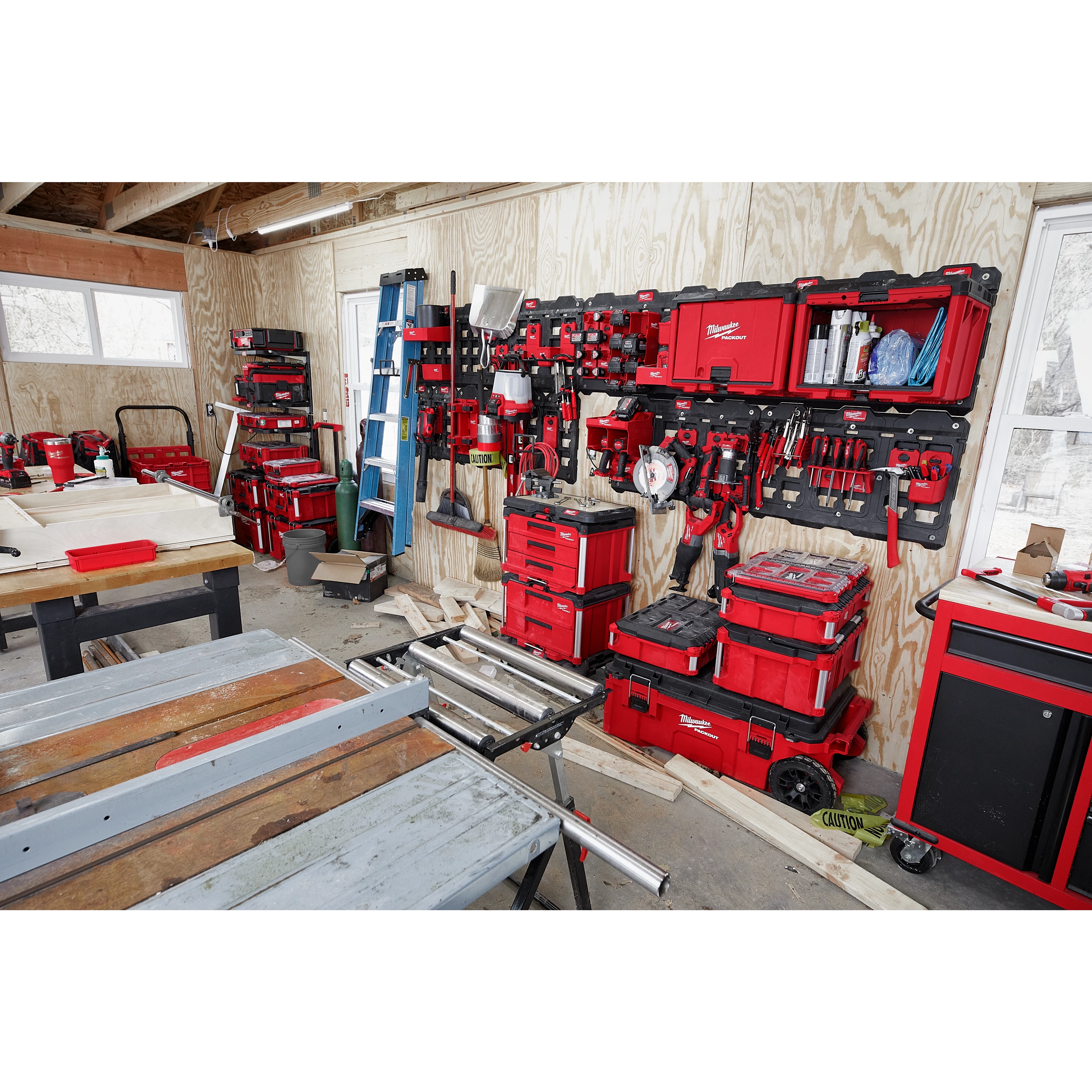 A workshop featuring the PACKOUT Large Wall Plate holding various red toolboxes, organizers, and tools mounted on a wooden wall.
