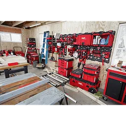 A workshop featuring the PACKOUT Large Wall Plate holding various red toolboxes, organizers, and tools mounted on a wooden wall.