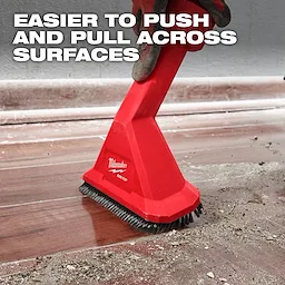 A red Milwaukee AIR-TIP™ Rocking Utility Nozzle with Brushes is shown being pushed across a dirty floor. Text at the top states: "Easier to Push and Pull Across Surfaces." The nozzle has bristles at the base for effective cleaning.