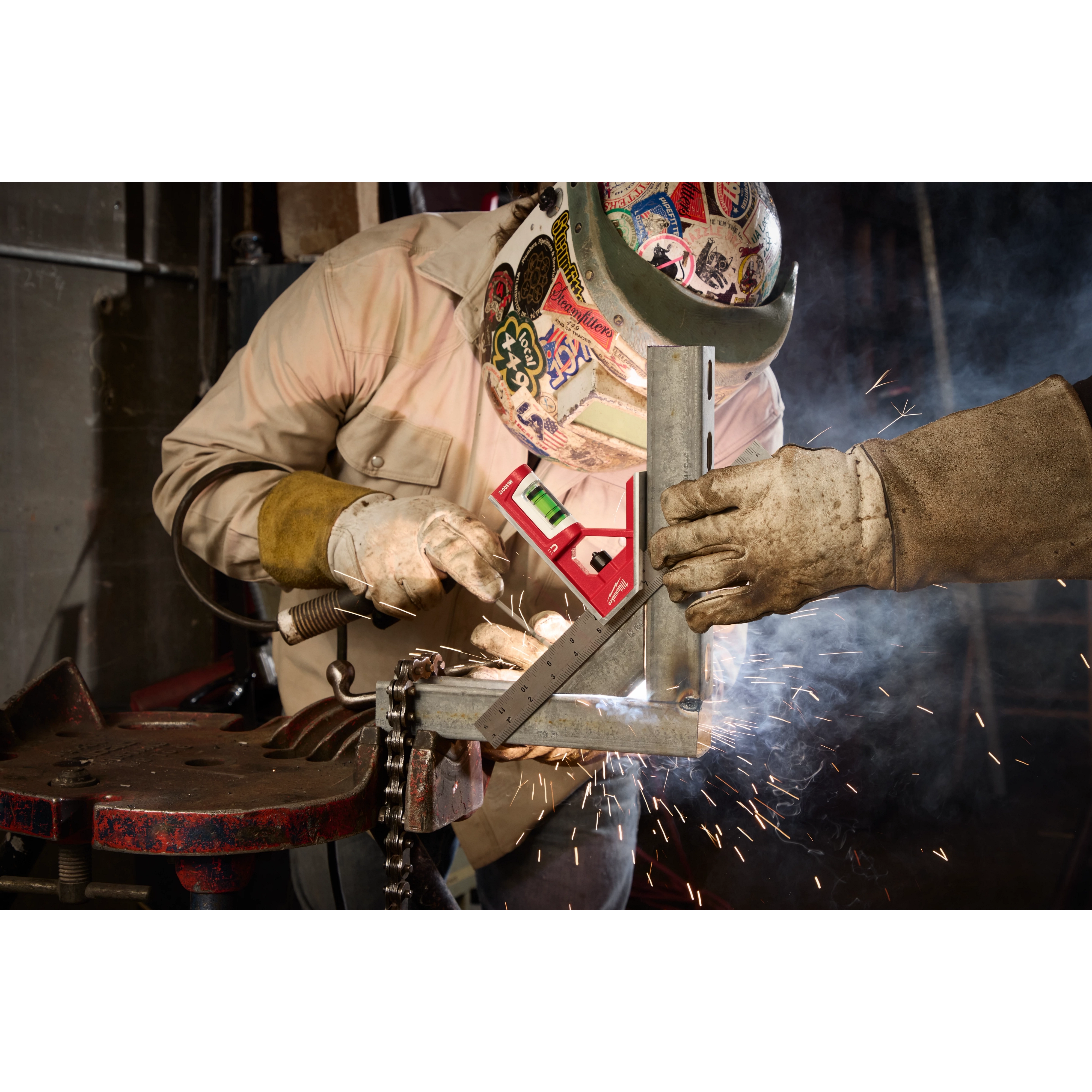 Welder using the 12" Magnetic Combination Square for precise measurements on a metal workpiece, with sparks in the background.
