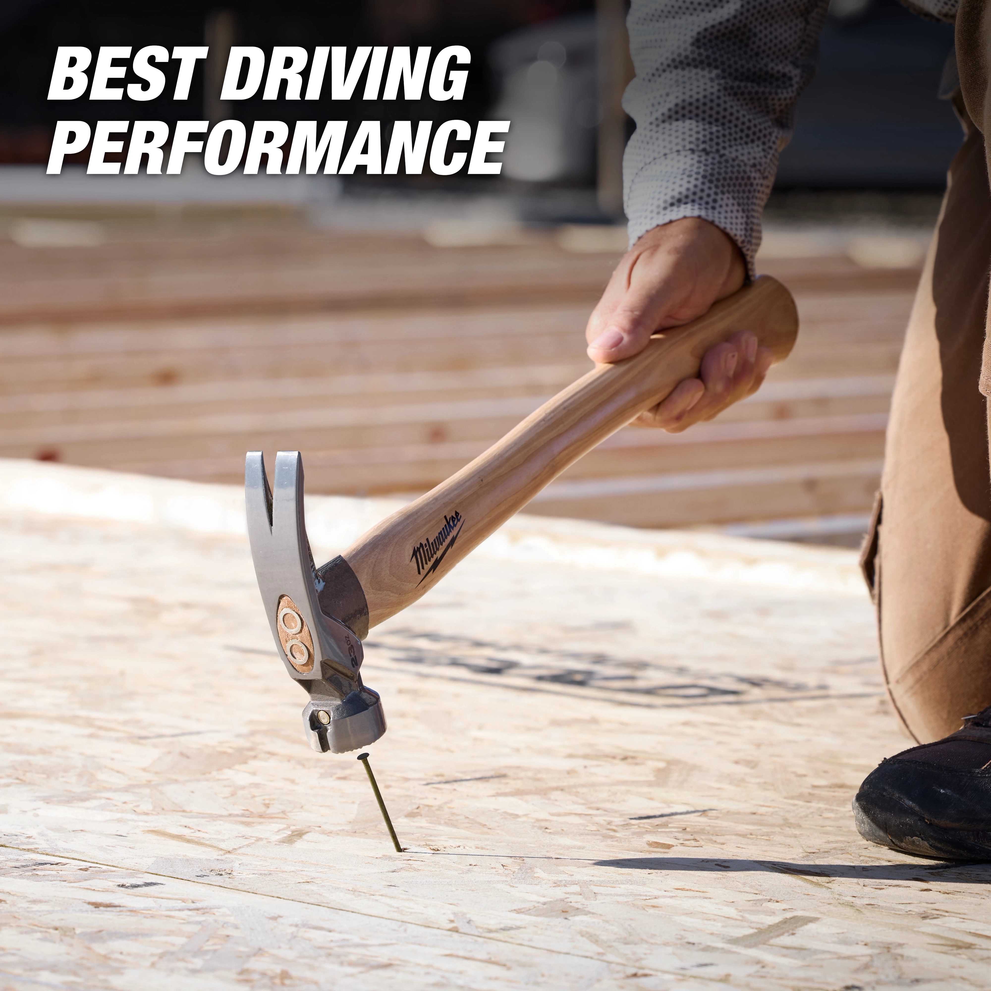 23oz Milled Face Hickory Handle Framing Hammer driving a nail into plywood on a construction surface.
