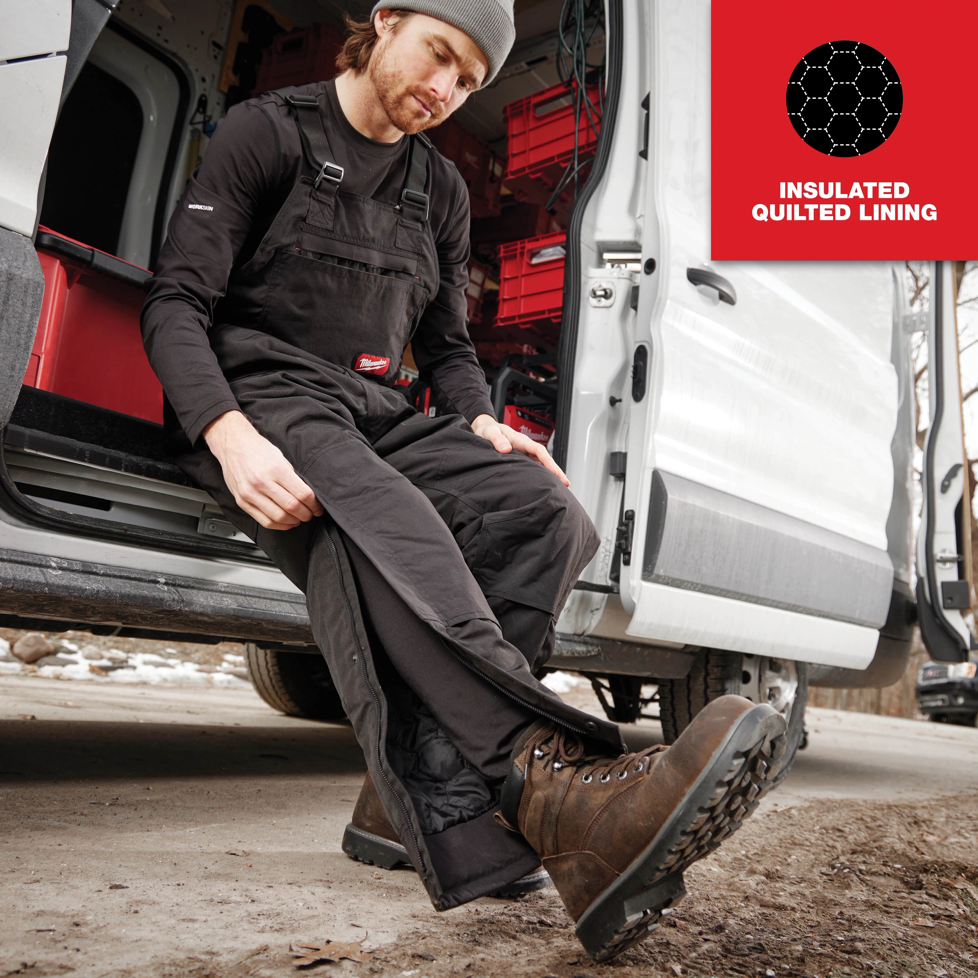 Man wearing Freeflex Insulated Bib Overalls with insulated quilted lining, sits on the step of a white van, showing its durability.