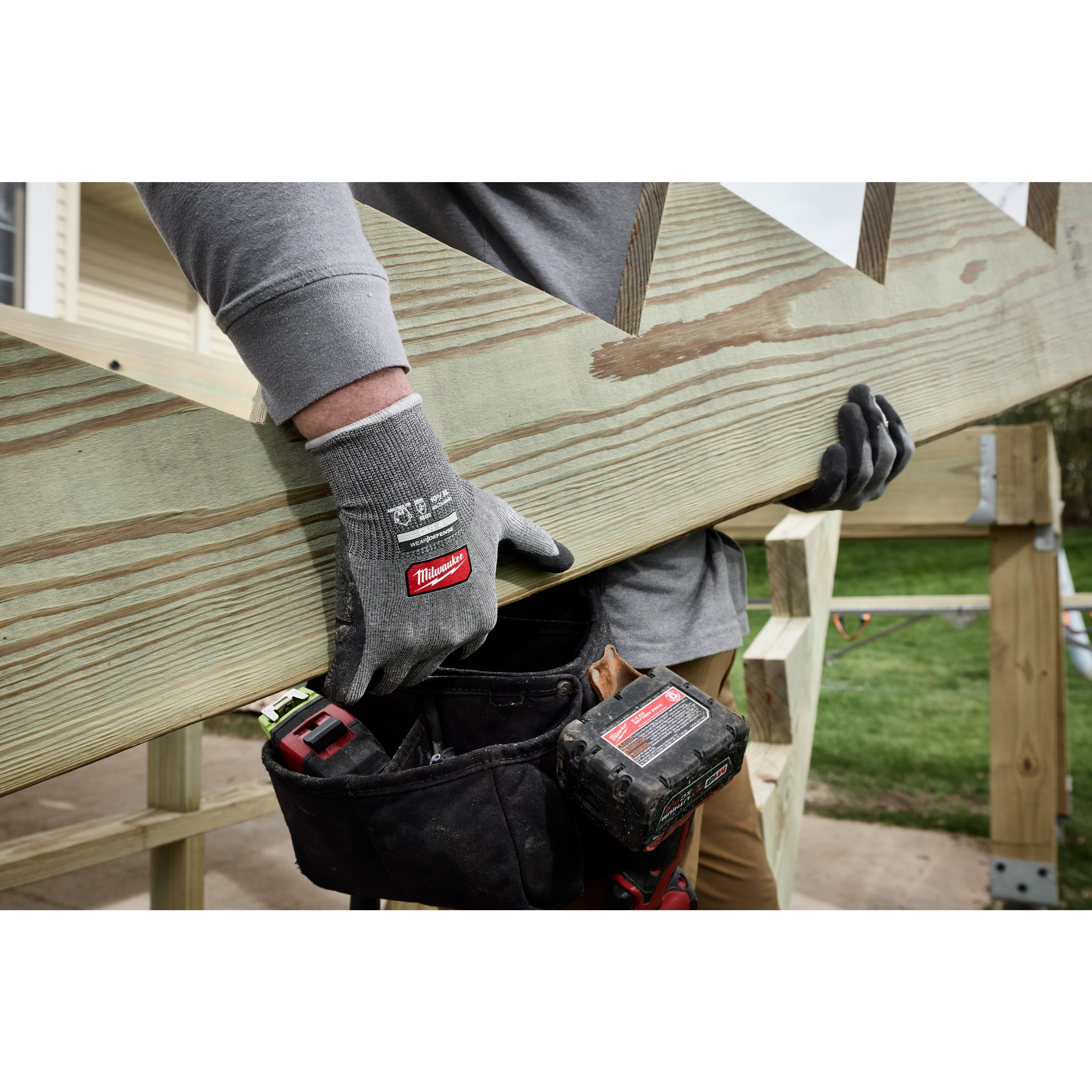 Worker lifting a wooden board while wearing Cut Level 4 High Dexterity Nitrile Dipped Gloves w/ WEAR-DEFENSE Protection.