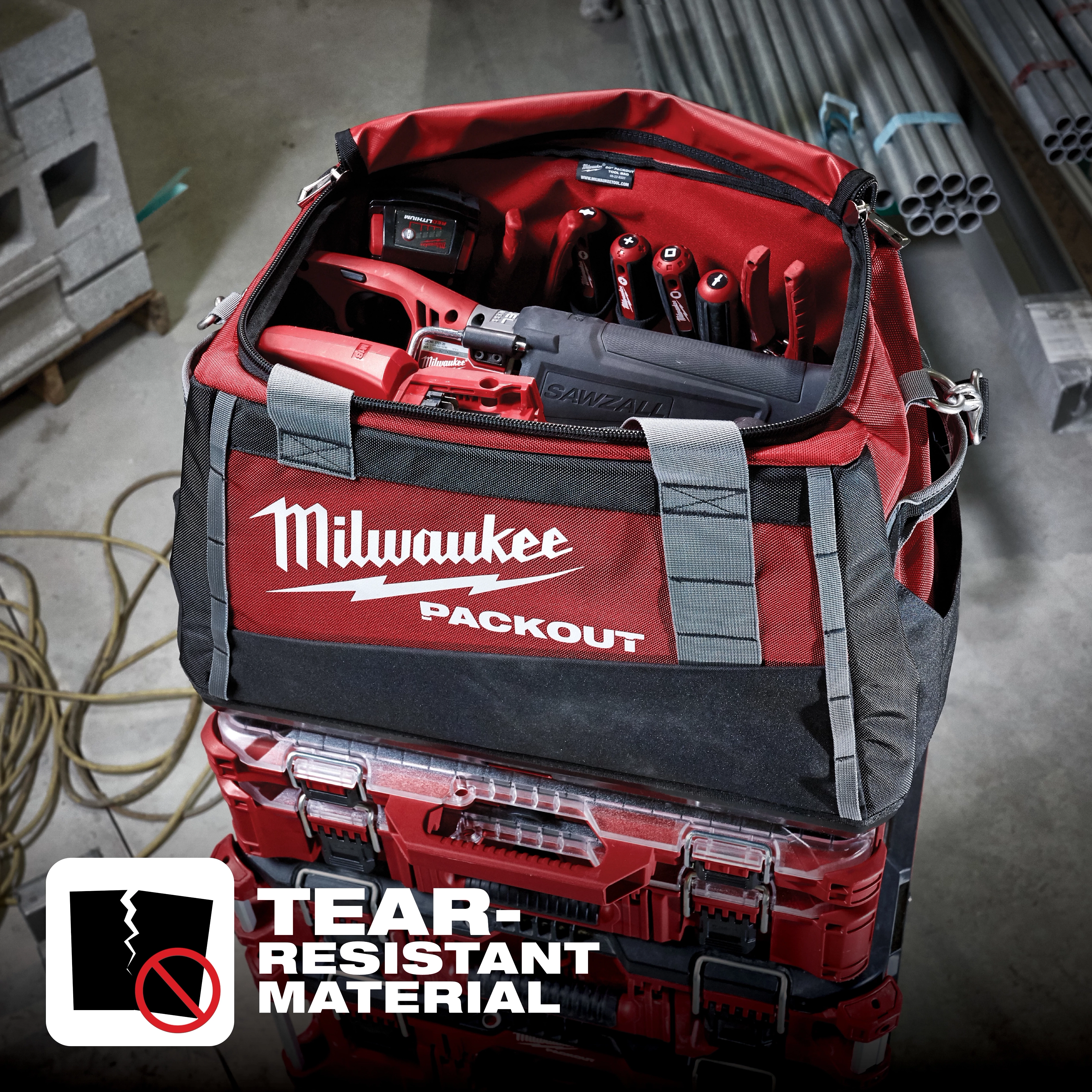 Milwaukee Packout tool bag filled with tools on top of Packout storage boxes. Tear-Resistant Material text and icon are visible.