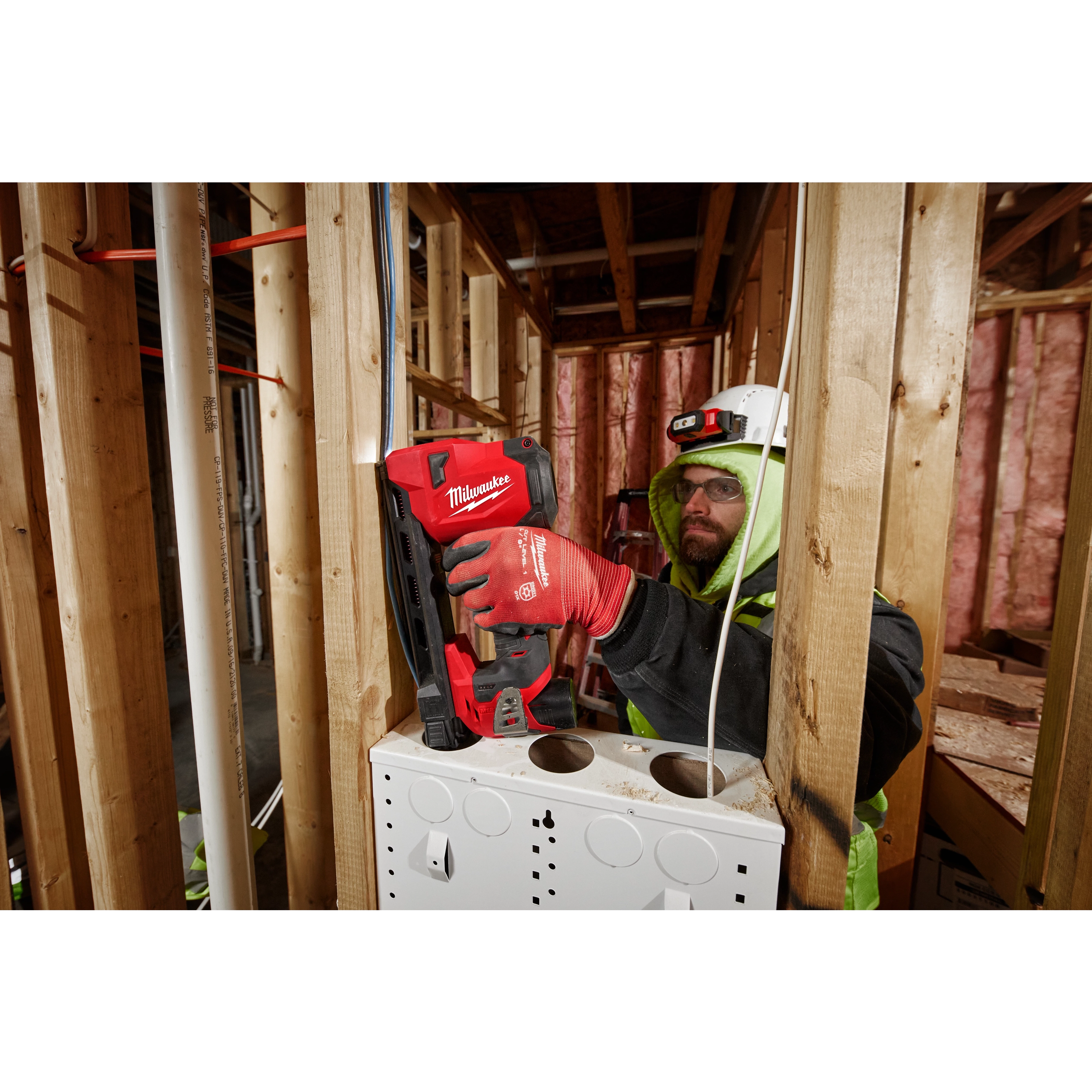 Worker using the M12 Cable Stapler with the attached LED Work light on the jobsite