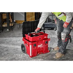 Image of a worker on a jobsite using the Milwaukee PACKOUT Rolling Tool Box with PACKOUT Tool Tray