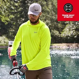 A person wearing a bright yellow WORKSKIN Hooded Sun Shirt and gloves is using a power tool near a pond. A "Trade Built Stretch" emblem is displayed in the top right corner.