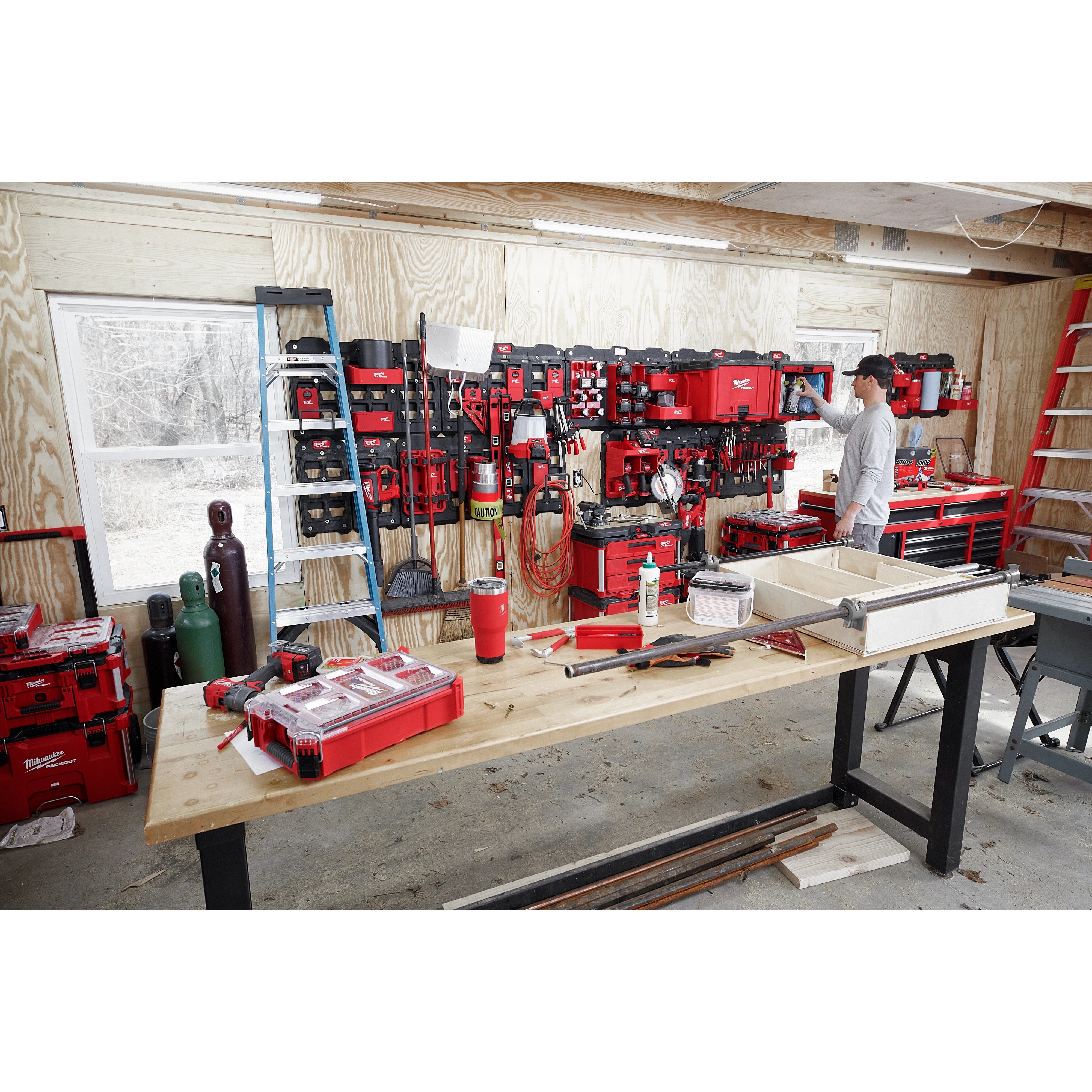 Workshop with a wall-mounted system showcasing the PACKOUT Large Wall Plate, holding various red and black tools and storage bins.