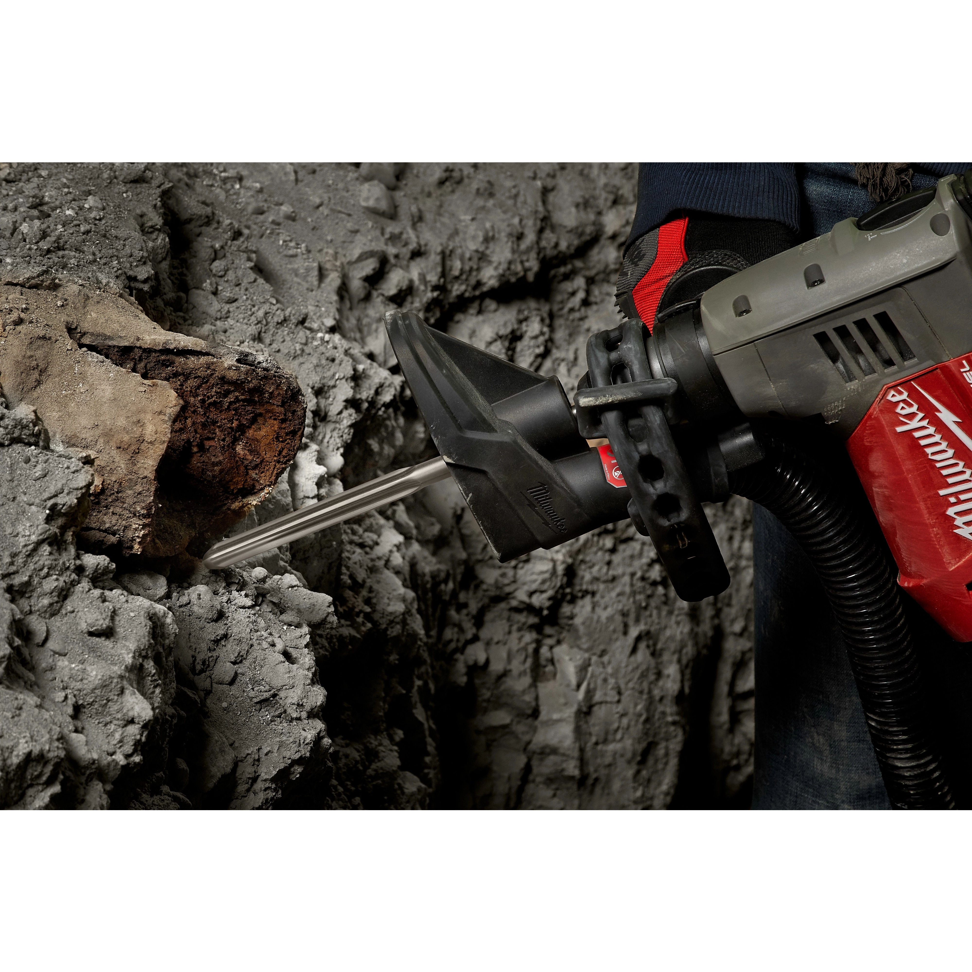 A person uses the SDS-Plus SLEDGE 10" Bull Point Chisel attached to a power tool to break through concrete.