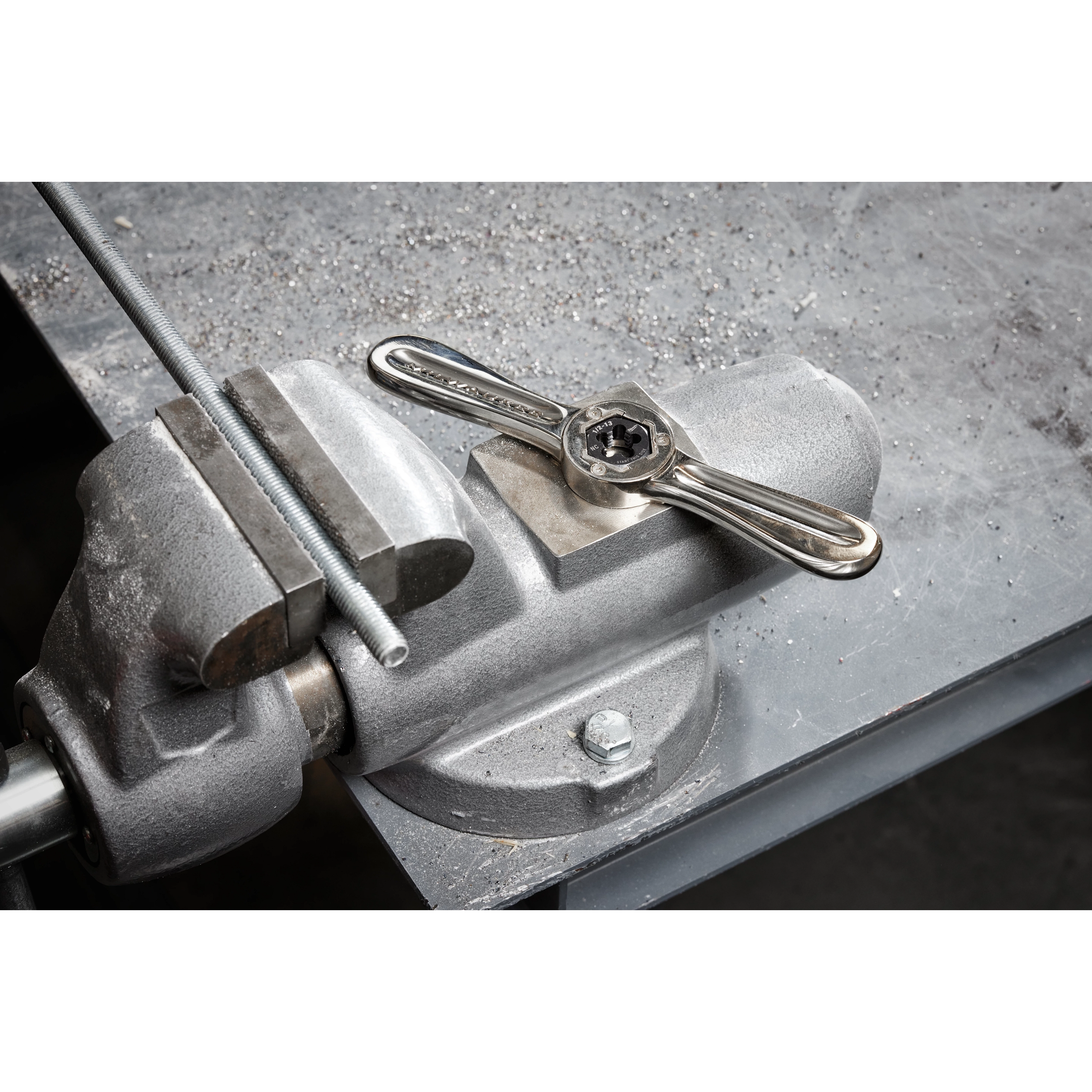 Hex-LOK 2-in-1 Threading Handle on a metal workbench, clamped, ready for use in threading operations.