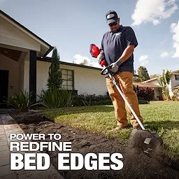Worker using M18 FUEL QUIK-LOK Bed Redefiner Attachment to edge a lawn beside a house.