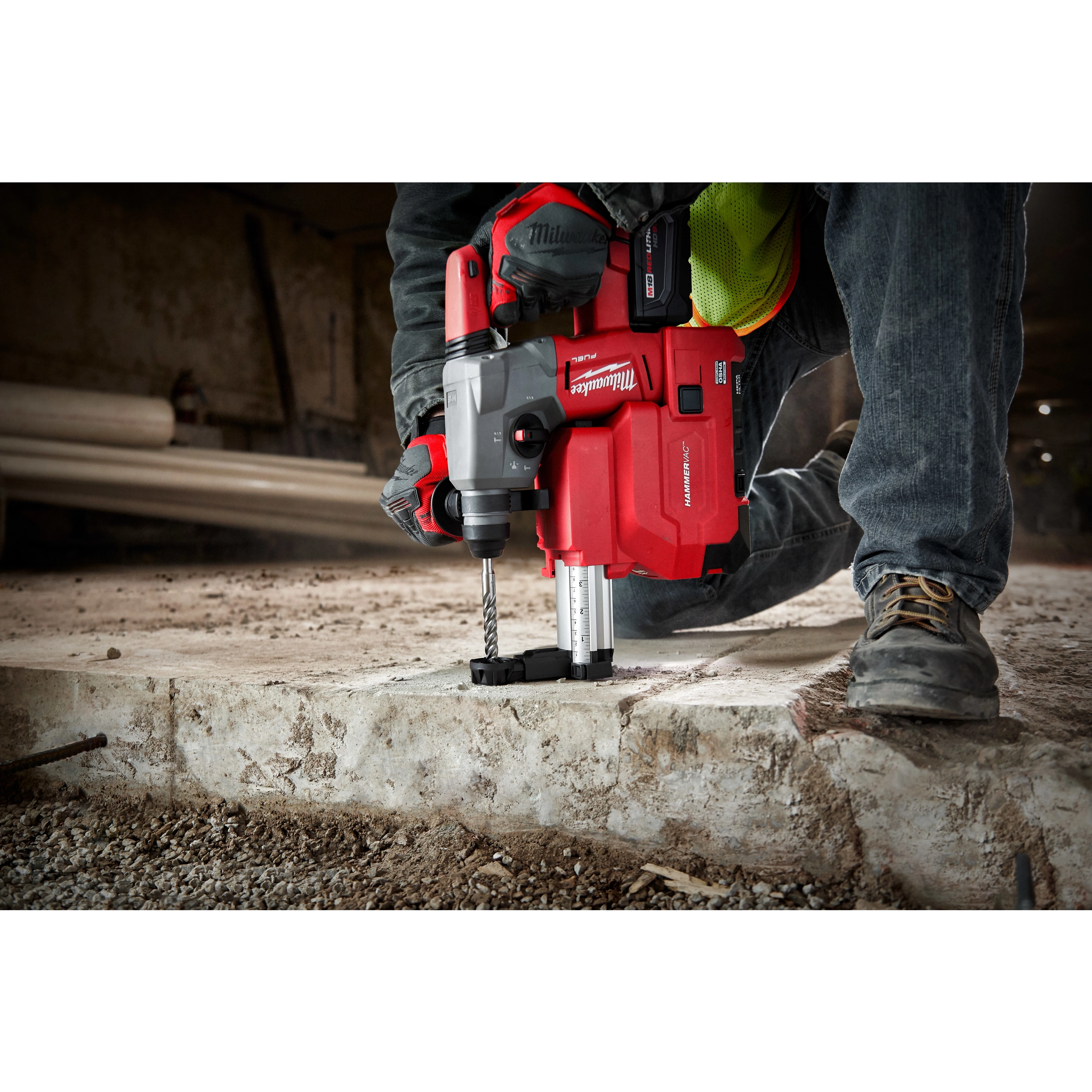 Worker using a red SDS+ MX4 1/2" X 4" X 6" rotary hammer drill to bore into a concrete surface at a construction site.