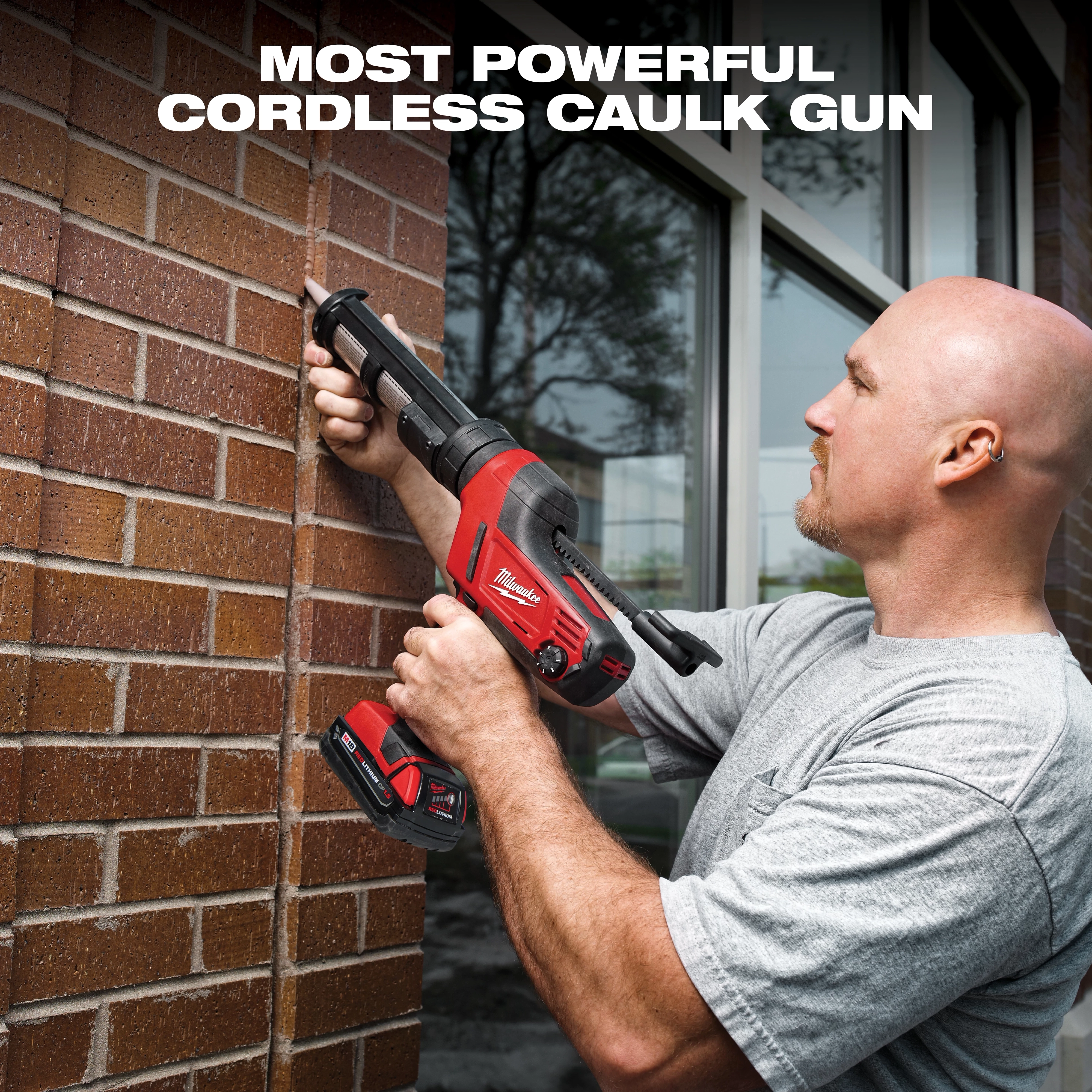 A person is using a red and black Milwaukee cordless caulk gun on a brick wall, standing in front of a window. The text "MOST POWERFUL CORDLESS CAULK GUN" is displayed at the top.