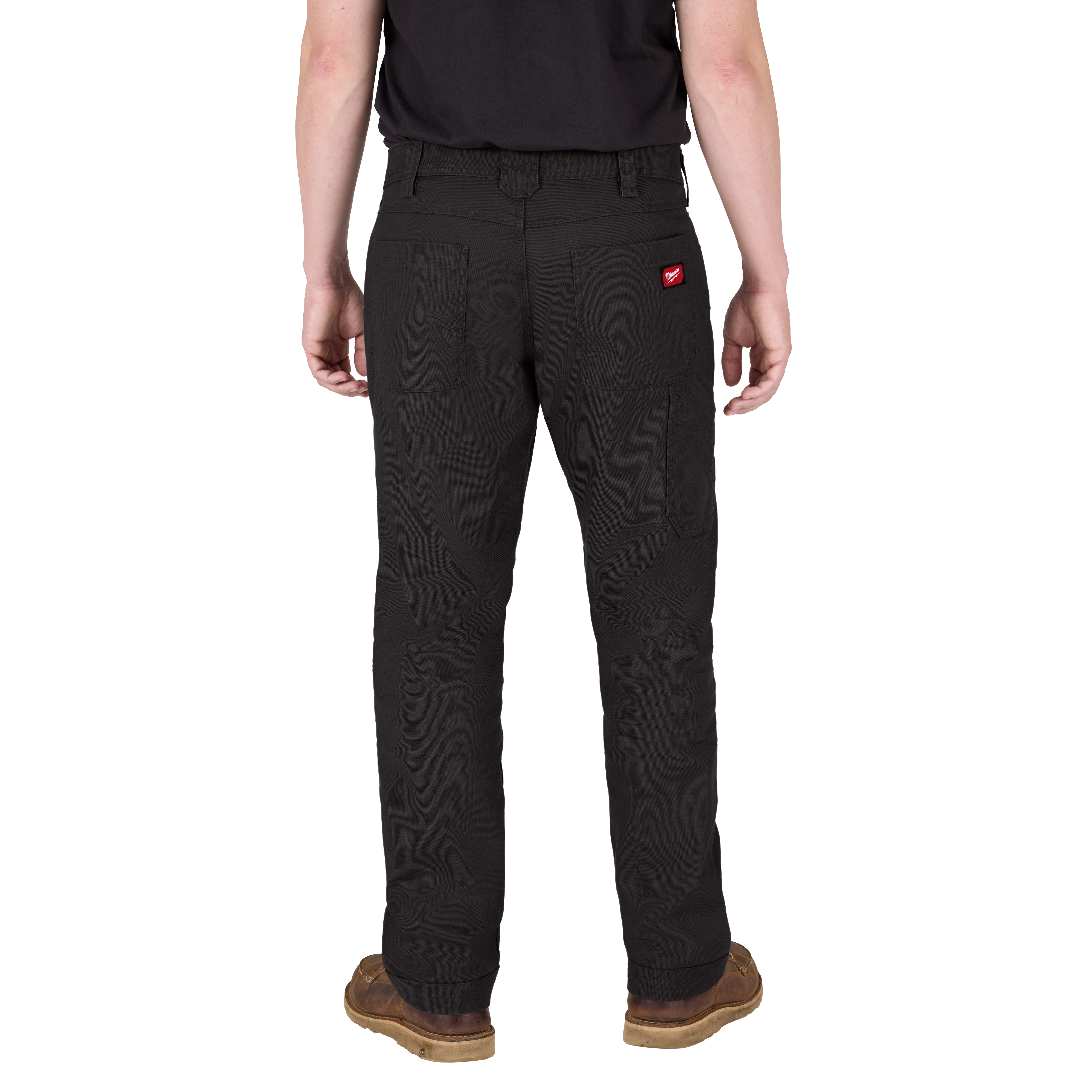 A person is shown from the back, wearing black work pants and brown work boots. The pants have two large back pockets, a side pocket on the right leg, and a small red logo on the right back pocket. They are also wearing a black shirt.