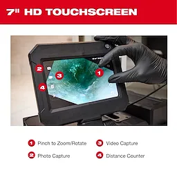 The image shows a close-up of the M12™ 75' Drain Camera w/ PACKOUT™ Compatibility's 7" HD touchscreen display. A gloved hand is using the pinch-to-zoom feature. The screen also highlights photo capture, video capture, and distance counter functionalities.