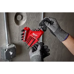Gloved hands hold the 9-Key Ball End L-Key Set - Metric in front of a concrete wall with visible electrical conduit.