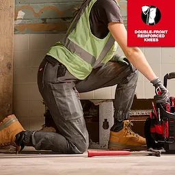 A woman is kneeling in a construction setting wearing Women's GRIDIRON™ Double Knee Jogger Pants, a safety vest, gloves, and work boots. The pants feature double-front reinforced knees. A red tool bag and tools are visible. A graphic label reads "DOUBLE-FRONT REINFORCED KNEES" at the top right.