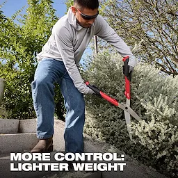 Person trimming a shrub on outdoor steps using 10” Hedge Shears with red and black handles.