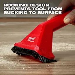 A person uses the AIR-TIP™ Rocking Utility Nozzle with Brushes on a surface with debris. The red nozzle has black bristles and displays the Milwaukee logo. Text above reads: "ROCKING DESIGN PREVENTS TOOL FROM SUCKING TO SURFACE."